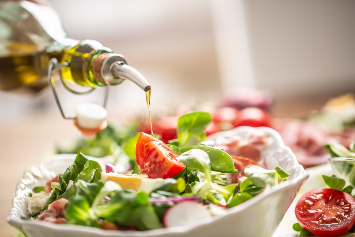 Frischer Salat wird mit hochwertigem Pflanzenöl beträufelt 