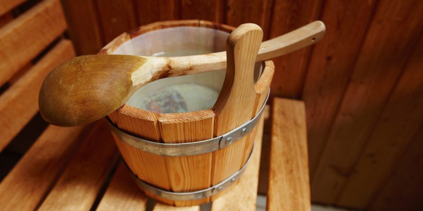 Holzeimer voll mit Wasser mit Schöpfkelle