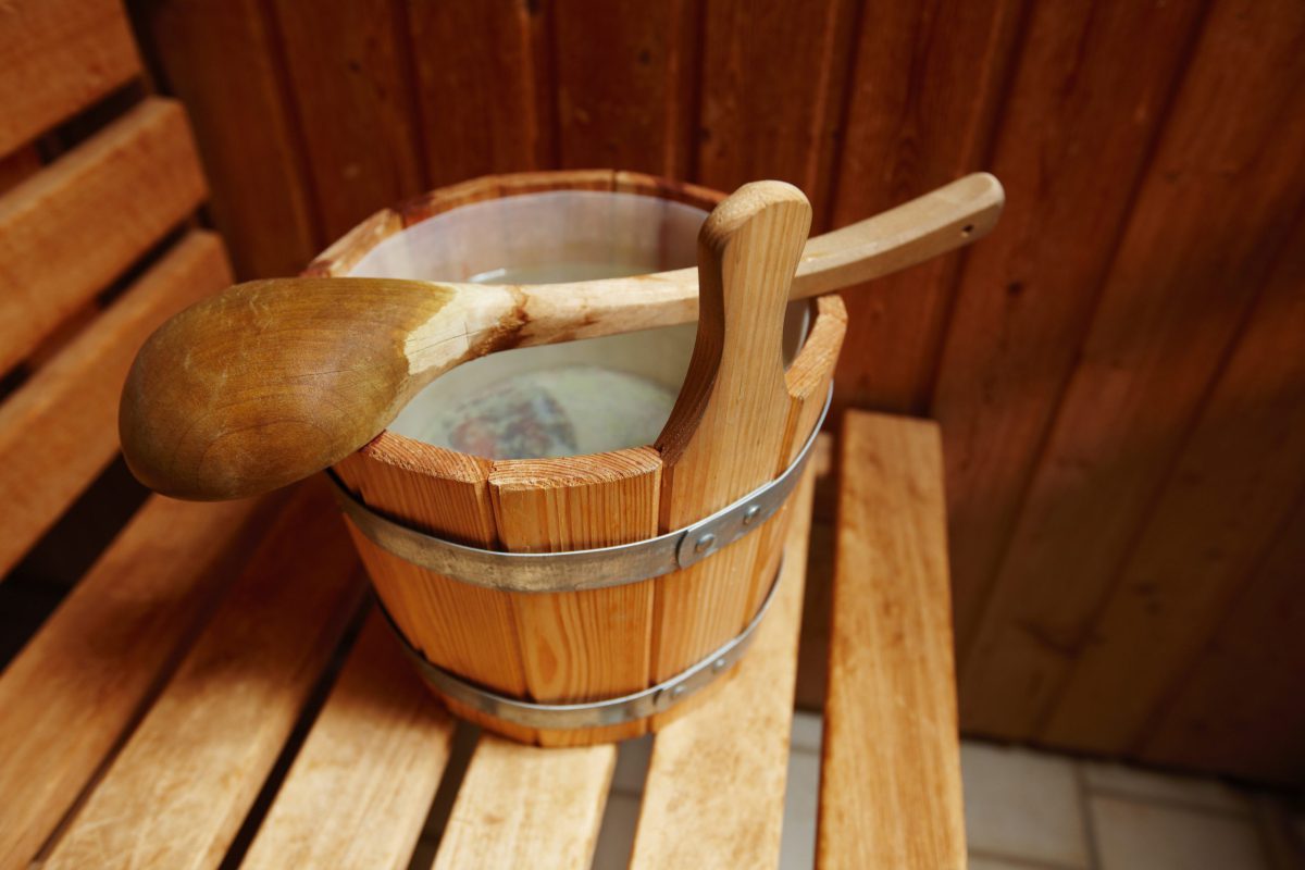 Holzeimer voll mit Wasser mit Schöpfkelle