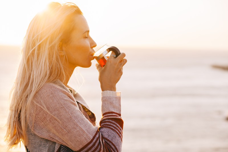 Frau-die-im-Sonnenuntergang-einen-Tee-trinkt